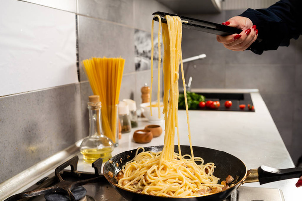 cropped shot of person cooking delicious italian pasta in kitchen - Foto, imagen