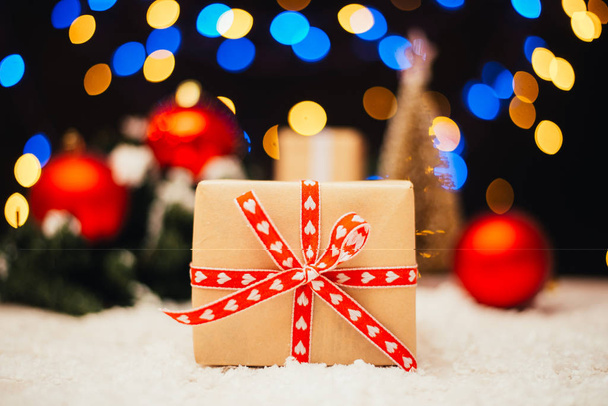 juhlava joulutausta lahjapakkauksella, kuusen oksilla ja punaisilla helyillä
 - Valokuva, kuva