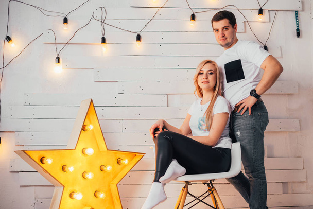 beautiful young couple posing together and smiling at camera in studio near illuminated star - Foto, imagen