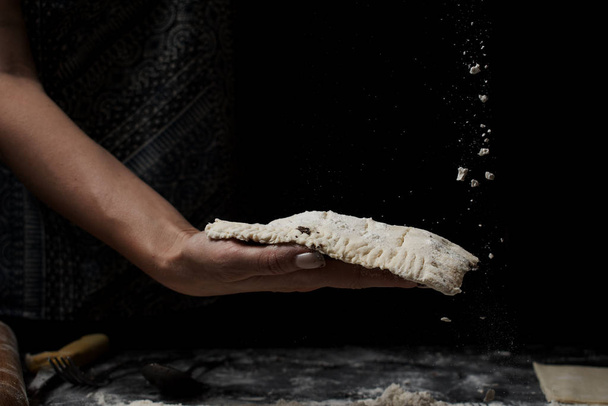 cropped shot of woman preparing fresh homemade dough on black background - Fotó, kép