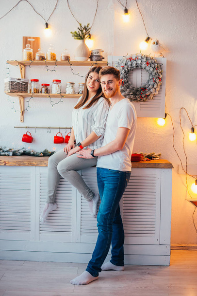 beautiful happy young couple smiling at camera in kitchen at christmastime - Foto, afbeelding