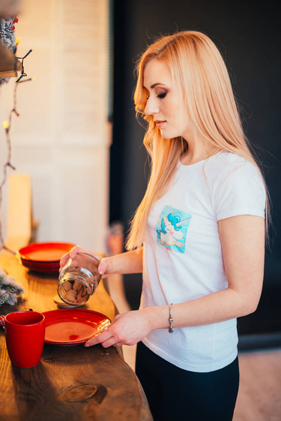 young blonde woman holding snacks in kitchen at christmastime - Φωτογραφία, εικόνα