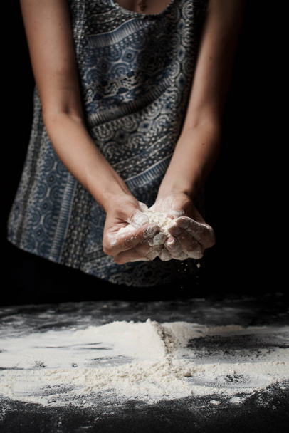 przycięty strzał kobiety przesiewania mąki i przygotowanie ciasta na czarnym tle - Zdjęcie, obraz
