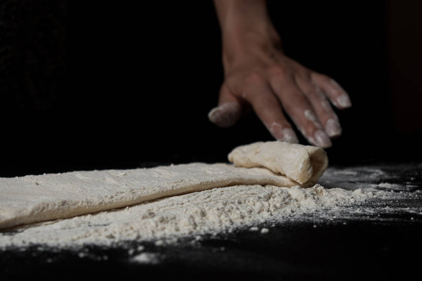partial view of woman preparing fresh homemade pastry on black background  - Fotó, kép