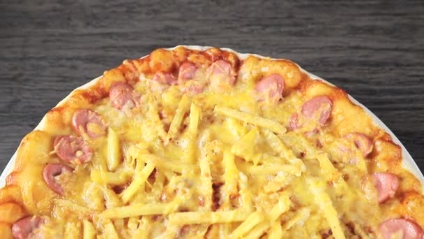 pizza de cerca con queso y salchicha que gira en torno a sí misma sobre una vista de fondo negro desde la parte superior
 - Metraje, vídeo
