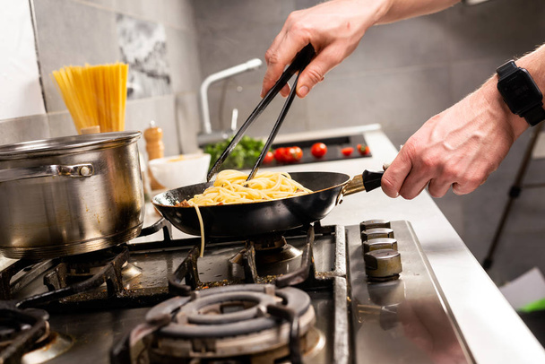 partial view of person cooking delicious italian pasta in kitchen - Foto, Bild