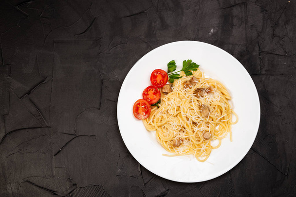 Carbonara pasta, spaghetti with pancetta, egg, hard parmesan cheese and cream sauce. Traditional italian cuisine. Pasta alla carbonara on black background. Top view - Photo, Image