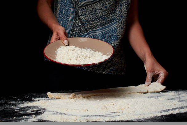 mid section of woman sifting flour and cooking dough on black background - Foto, Imagem