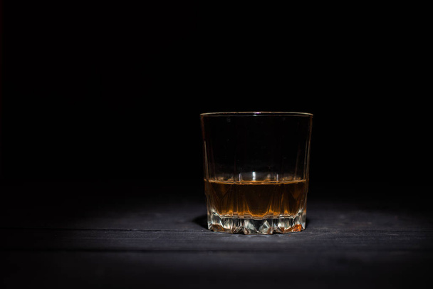 glass of whiskey with ice cubes on wooden table   - Photo, Image