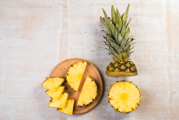 top view of fresh sliced pineapple on wooden board on light background  - Foto, imagen