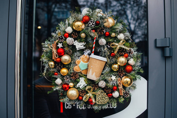 キラキラした装飾が施されたクリスマスリースジンジャーブレッドクッキーとペーパーカップ - 写真・画像