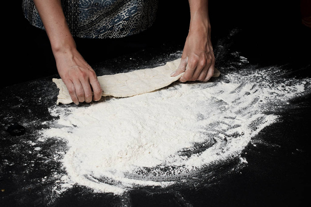 cropped shot of woman preparing fresh uncooked dough on black surface - Photo, Image