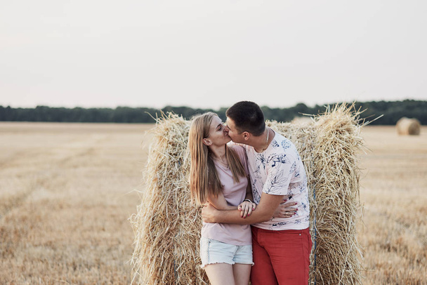 beautiful happy young couple near hay bales in field during harvest - Zdjęcie, obraz