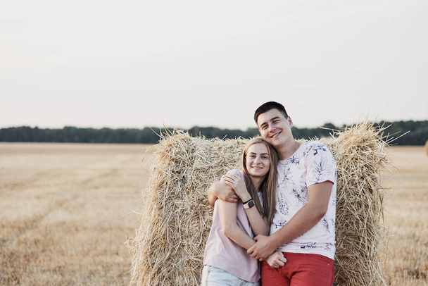 beautiful happy young couple near hay bales in field during harvest - Foto, Bild