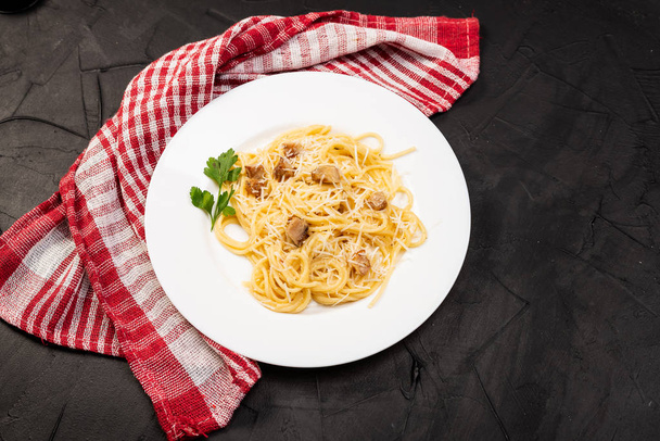 Carbonara pasta, spaghetti with pancetta, egg, hard parmesan cheese and cream sauce. Traditional italian cuisine. Pasta alla carbonara on black background. Top view - Φωτογραφία, εικόνα
