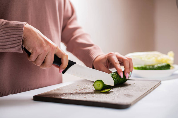 close-up partial view of woman chopping fresh cucumber for healthy salad   - Photo, Image