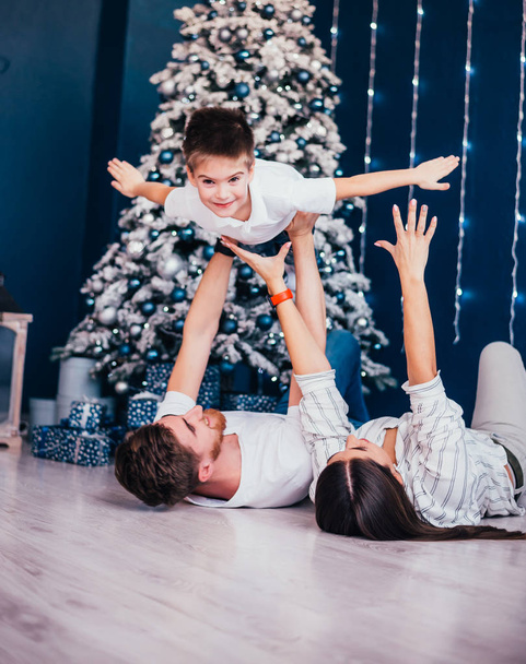 happy young family with adorable little son having fun together near christmas tree - Photo, Image