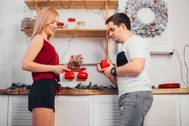 happy young couple standing together in kitchen at christmastime - Valokuva, kuva