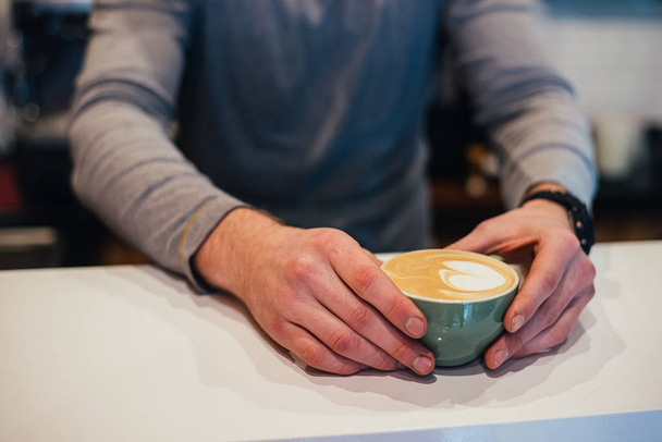 cropped shot of man holding cup of coffee while sitting in cafe - Foto, imagen