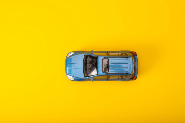 small blue car model on yellow background.  - Zdjęcie, obraz
