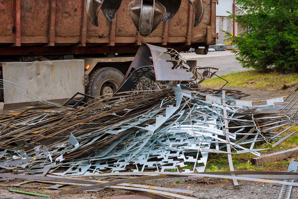 Ένα φορτηγό αρπαγής φορτώνει παλιοσίδερα για ανακύκλωση. - Φωτογραφία, εικόνα