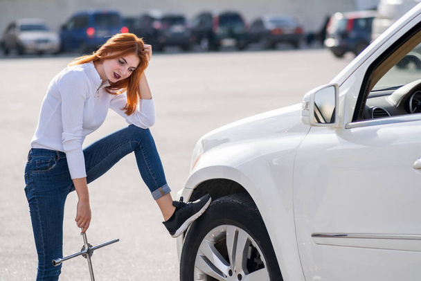Young woman with wrench waiting for help to change wheel - Foto, Bild