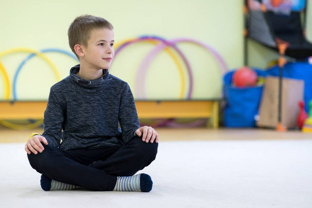 Fiatal gyermek fiú ül és relaxációg a padlón belül sport - Fotó, kép