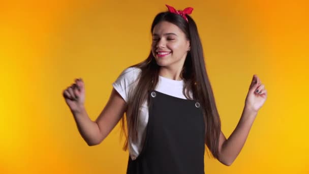 Pretty girl in dress smiling and dancing in excellent mood on yellow background. Happiness, party concept. - Imágenes, Vídeo