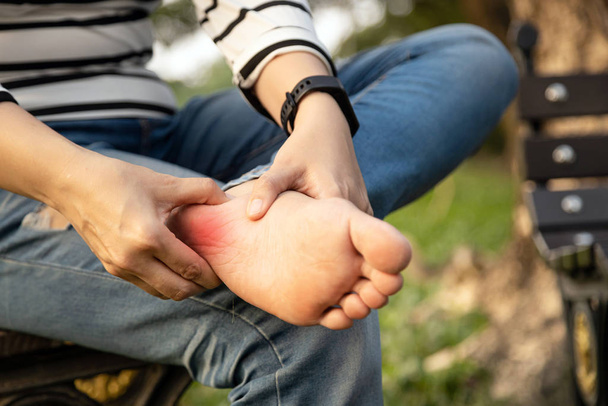 Closeup pé de uma mulher jovem asiática segurando seus pés e massagem com a mão sofrem de inflamação do tendão, pessoas do sexo feminino pé dolorido, dor no calcanhar, fadiga perna, problema de saúde, conceito fascite plantar
 - Foto, Imagem