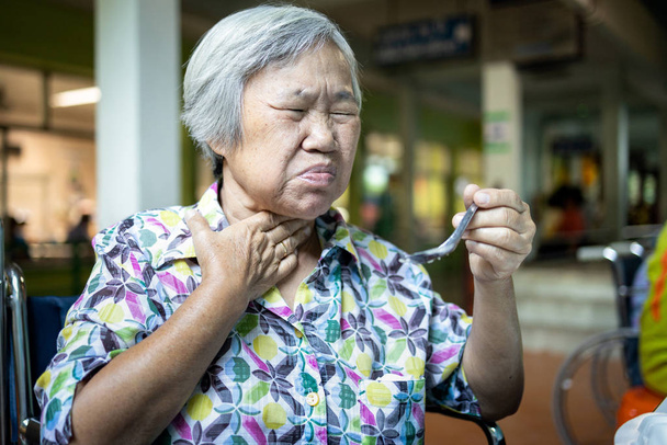 Ázsiai idős nő szenved fulladás, eltömődött élelmiszer, idősek fuldokló etetés közben, élelmiszer ragadhat a torokban, és megfullad az elválasztó fájdalom sérülés, egészségügyi probléma, fulladás, fulladás  - Fotó, kép
