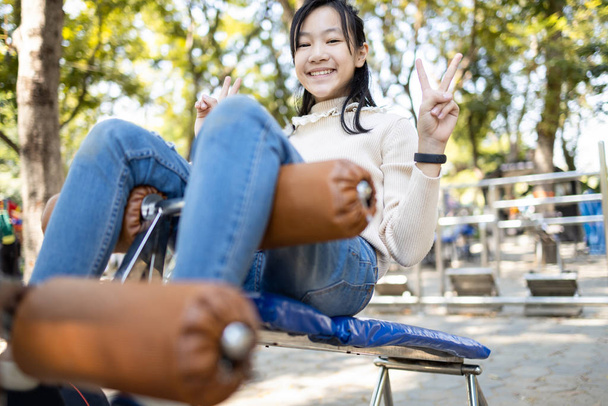 Hermosa niña asiática practicando fitness, haciendo ejercicio sentado para la salud y la fuerza en el parque de la ciudad, feliz adolescente sonriente haciendo abdominales sentadas en el gimnasio al aire libre, concepto de cuidado de la salud
 - Foto, imagen