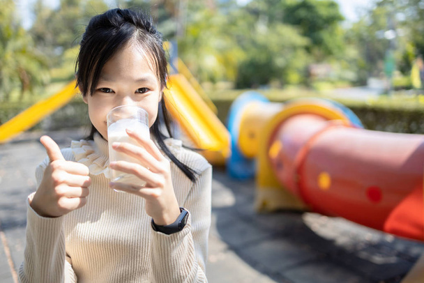 Smiling asian teenager girl drinking a glass of milk,enjoying an - 写真・画像