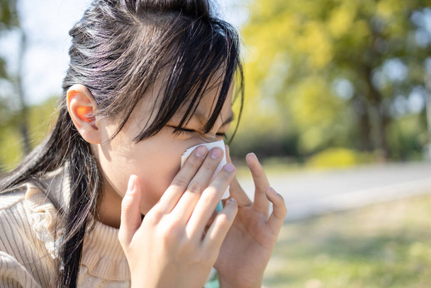 Sick asian child girl sneezing in a tissue blowing her runny nos - 写真・画像
