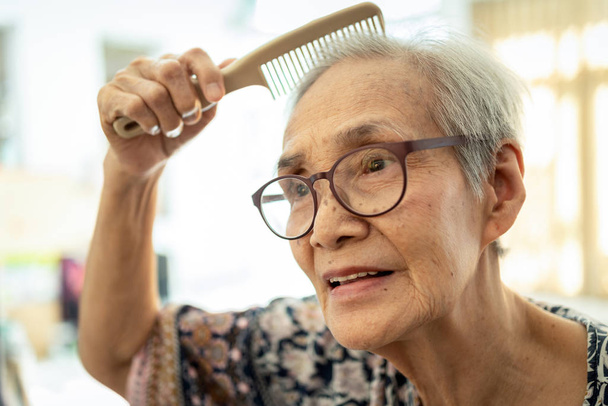 Detailní záběr na tvář krásných starých lidí kartáčování vlasů s hřebenem v ruce, šťastný asijský senior žena těšit česání vlasů, čisté vlasy zdravé ženy, žena starší péče o její vlasy, krása koncepce  - Fotografie, Obrázek