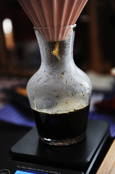 Origami-Filter tropft Kaffee in eine Glaskaraffe aus nächster Nähe. elektronische Waage. Alternatives manuelles Brauen - Foto, Bild
