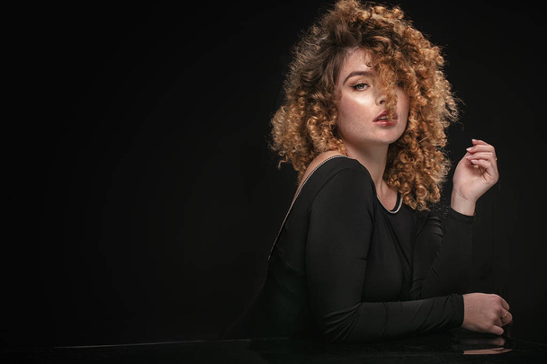 Elegant woman with curly hair posing. - Фото, изображение