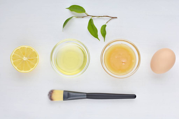 Σπιτική μάσκα προσώπου για το δέρμα ακμής, φυσικά συστατικά, μέλι, ασπράδι αυγού, λεμόνι, επίπεδη θέσει σε λευκό φόντο. - Φωτογραφία, εικόνα