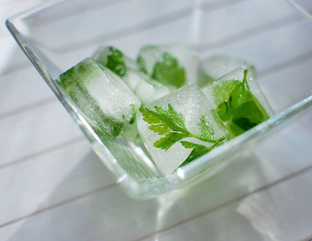 Ice cubes with frozen parsley in glass bowl. - Foto, Bild