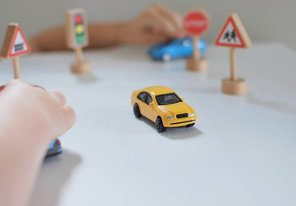 Bambini che giocano con auto giocattolo, cartelli stradali, concentrarsi sulla macchina gialla
. - Foto, immagini