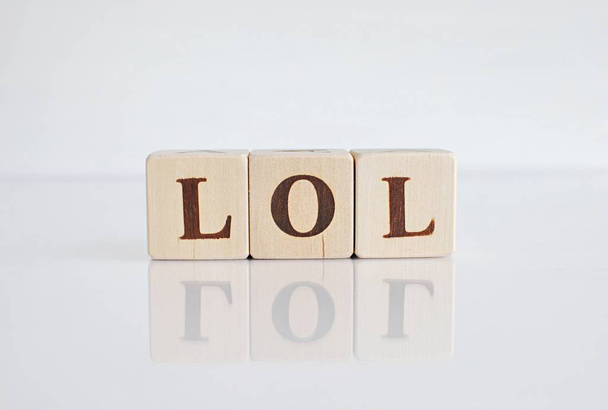 Λέξη Lol ή γέλιο φωναχτά γίνεται με ξύλινα μπλοκ σε λευκό φόντο. - Φωτογραφία, εικόνα