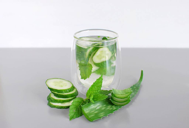 Acqua infusa in grande bicchiere, con cetriolo, foglie di menta, limone verde, spazio per la copia
. - Foto, immagini
