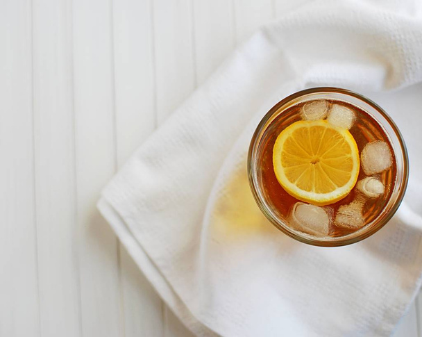 Ice tea with lemon. Top view on white napkin and white wooden table. - Fotoğraf, Görsel