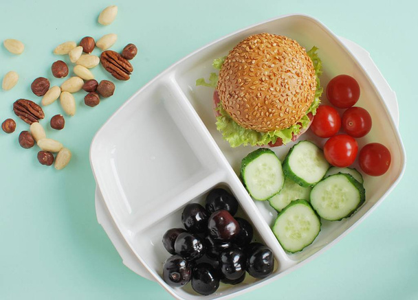 Lunchdoos met broodje, noten, kersen, groenten. Gezonde lunchbox voor kinderen. - Foto, afbeelding