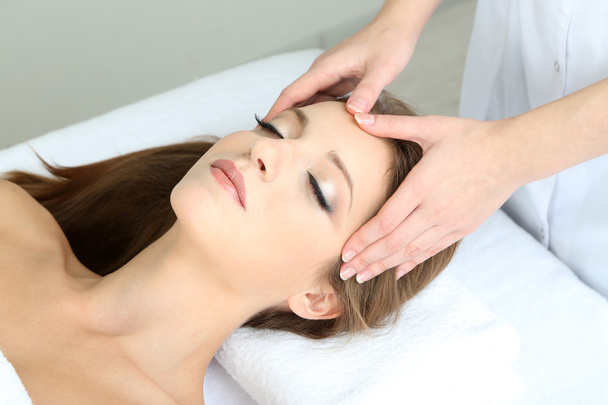 Beautiful young woman during facial massage in cosmetic salon close up - Photo, Image