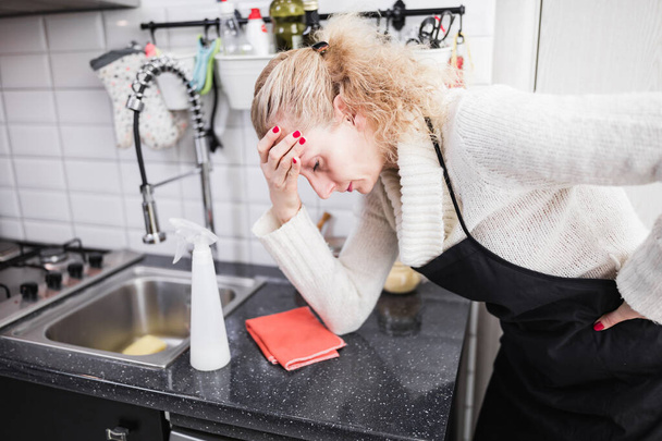 Vrouw moe van het schoonmaken van het huis, keuken en het doen van dagelijkse hou - Foto, afbeelding
