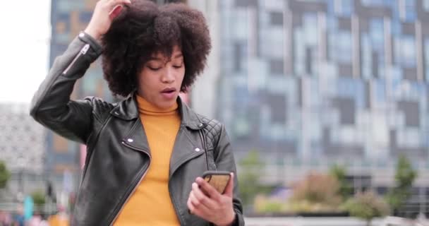 African American young adult female using smartphone in city - Imágenes, Vídeo