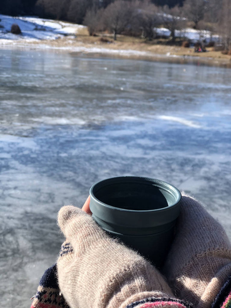 xícara de bebida quente em mãos close-up em todo o lago congelado. Paisagem de inverno. Acampar. Actividade de Inverno
 - Foto, Imagem