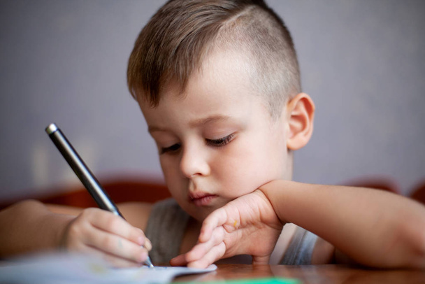 Detailní portrét roztomilého chlapečka kreslícího obrázek. Krásná, emocionální tvář čtyřletého dítěte. - Fotografie, Obrázek