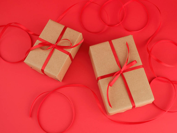 boîte enveloppée dans du papier kraft brun et attachée avec une fine soie r rouge
 - Photo, image
