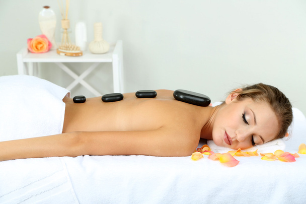 Beautiful young woman having stone massage in spa salon - Fotografie, Obrázek